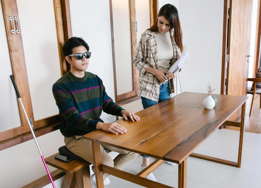 An instructor assessing a blind person sitting on an office table