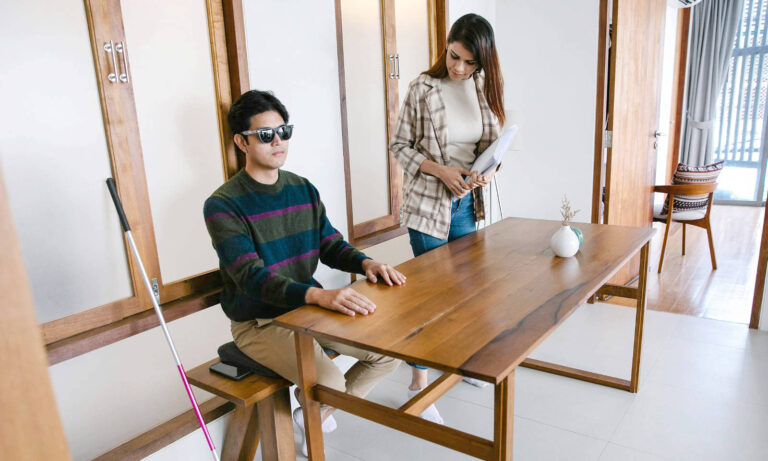 An instructor assessing a blind person sitting on an office table