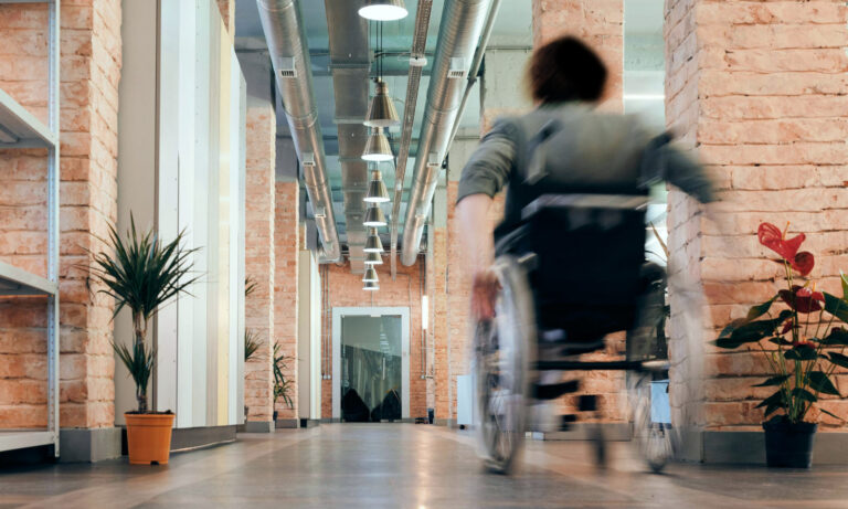 Wheelchair user moving in an office corridor