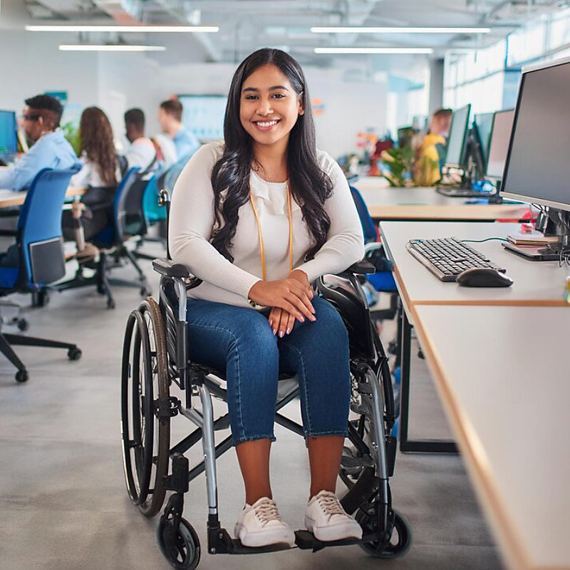 Women on a wheelchair smiling, in an office environment